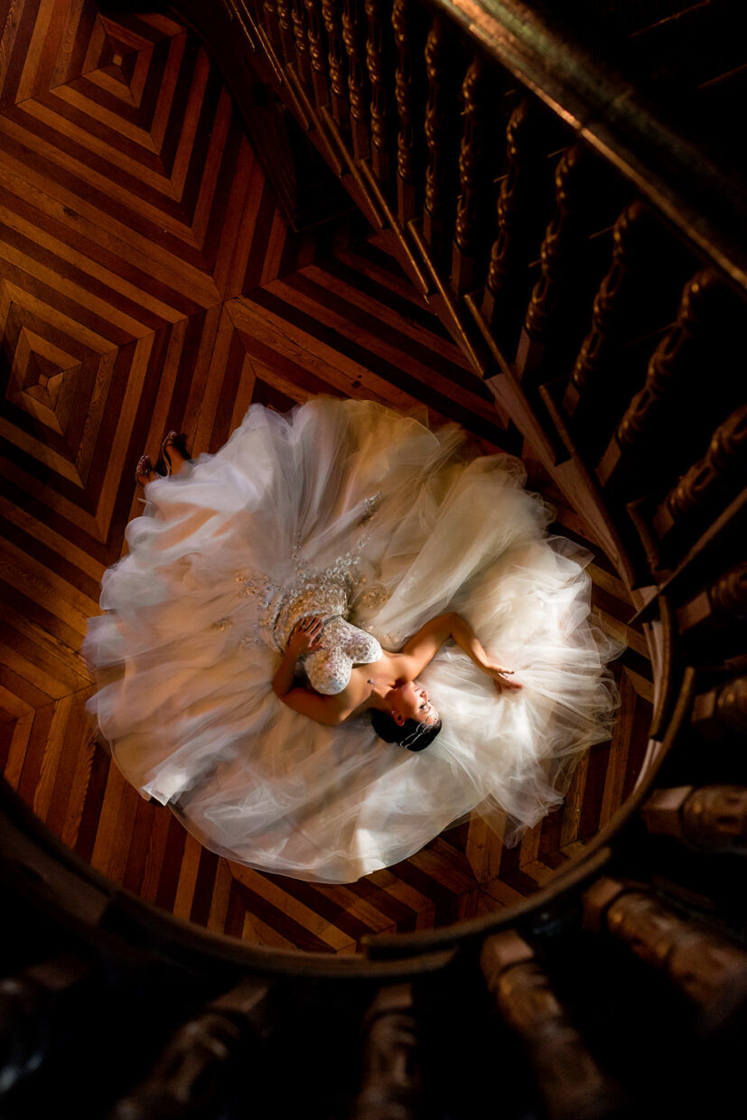 This wedding was in Baltimore Maryland, the bride was laying at the bottom of the stairs, her dress is spread out in a giant circle, she is literally lying on the floor in an etherial pose, her face is lit by an off camera flash and the photo is an arial shot from the top of the winding staircase, Procopio Photography, best top Washington DC photographer, best top Maryland photographer, best top Virginia photographer, best top DMV photographer, best top wedding photographer, best top commercial photographer, best top portrait photographer, best top boudoir photographer, modern fine art portraits, dramatic, unique, different, bold, editorial, photojournalism, award winning photographer, published photographer, memorable images, be different, stand out