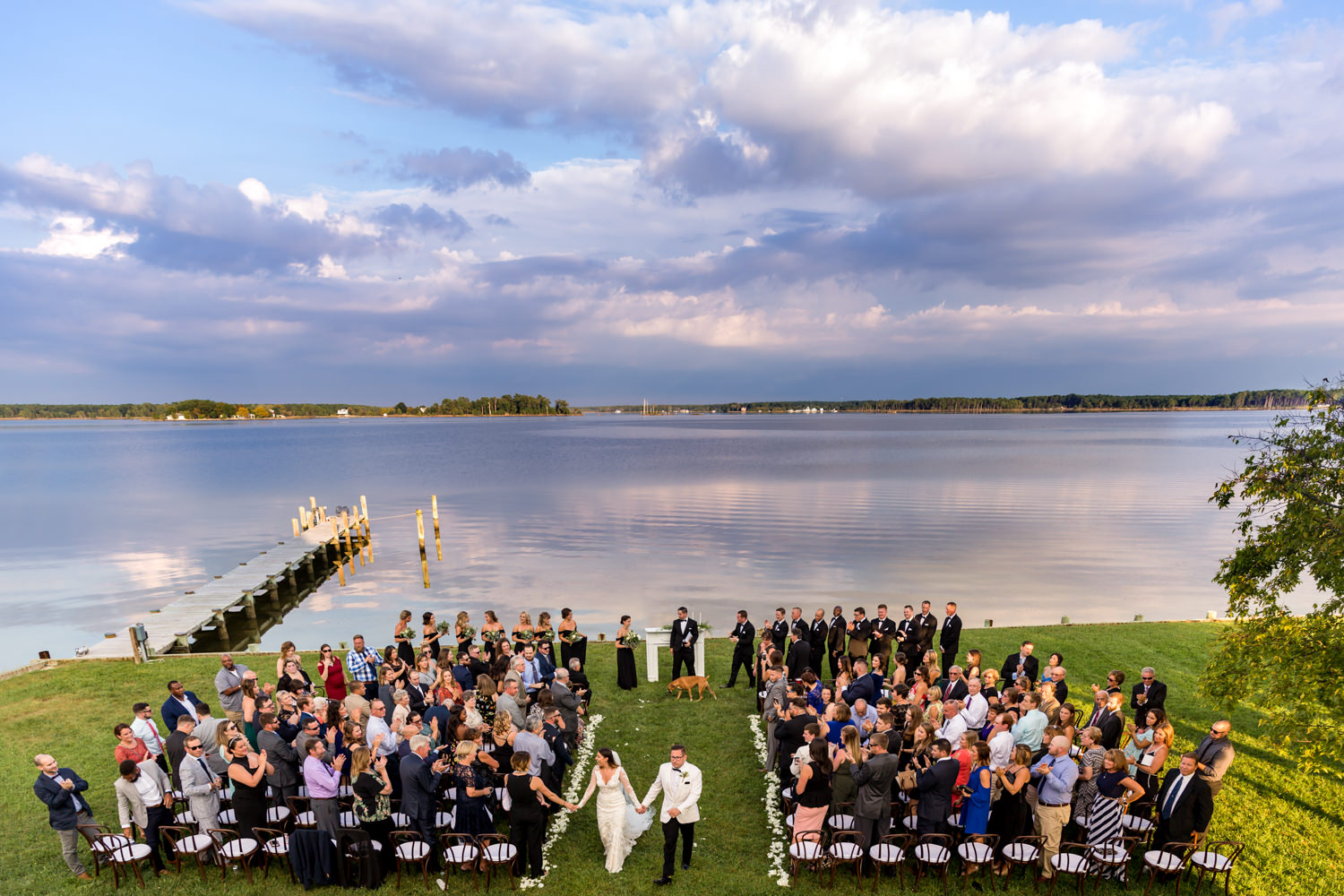 This was an Eastern Shore Maryland Wedding, Swan Cove Manor, I photographed the ceremony recessional from the roof of a nearby house, The couple and the entire wedding can be seen at the last moment of their recessional almost walking off frame in an arial view, The clouds and ocean behind them make an incredibly romantic backdrop, The guests cheer as the newly married couple walks back down the aisle, Their dog was their ring bearer, Be different, Procopio Photography, best top Washington DC photographer, best top Maryland photographer, best top Virginia photographer, best top DMV photographer, best top wedding photographer, best top commercial photographer, best top portrait photographer, best top boudoir photographer, modern fine art portraits, dramatic, unique, different, bold, editorial, photojournalism, award winning photographer, published photographer, memorable images, be different, stand out