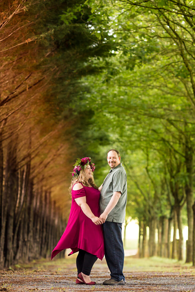 This was a Renaissance Festival themed engagement session, the couple is standing under a row of trees canopy over their heads, the left half of the row of trees is turning orange for the fall and the right half is still green giving the photo a really cool split color look of the background, the gal is in pink with a crown of flowers on her head, Procopio Photography, best top Washington DC photographer, best top Maryland photographer, best top Virginia photographer, best top DMV photographer, best top wedding photographer, best top commercial photographer, best top portrait photographer, best top boudoir photographer, modern fine art portraits, dramatic, unique, different, bold, editorial, photojournalism, award winning photographer, published photographer, memorable images, be different, stand out, engagement photography