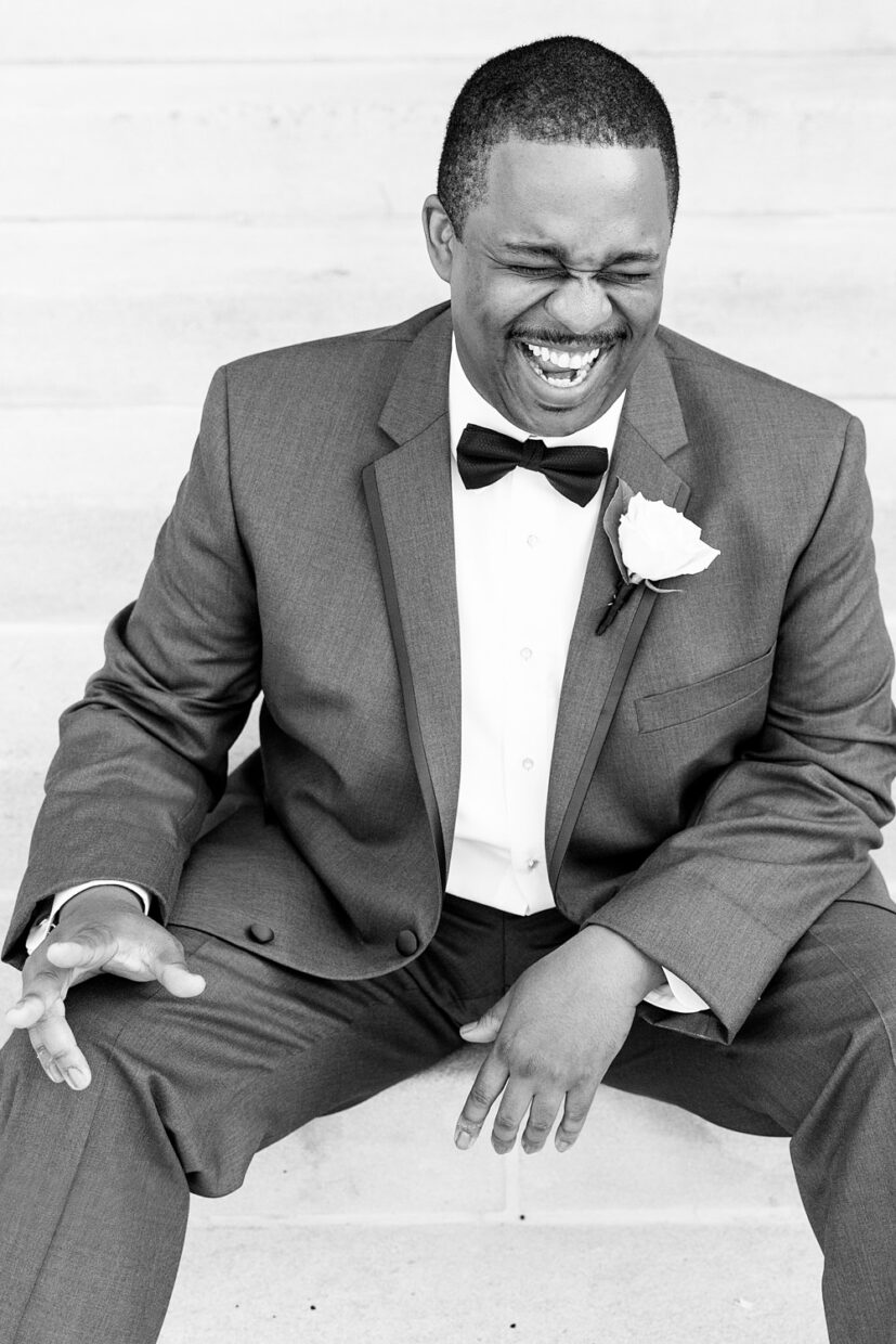 Carnegie Institution of Science wedding, this is a black groom and a black and white photo, he is sitting on the stairs outside laughing hysterically, Procopio Photography, best top Washington DC photographer, best top Maryland photographer, best top Virginia photographer, best top DMV photographer, best top wedding photographer, best top commercial photographer, best top portrait photographer, best top boudoir photographer, modern fine art portraits, dramatic, unique, different, bold, editorial, photojournalism, award winning photographer, published photographer, memorable images, be different, stand out