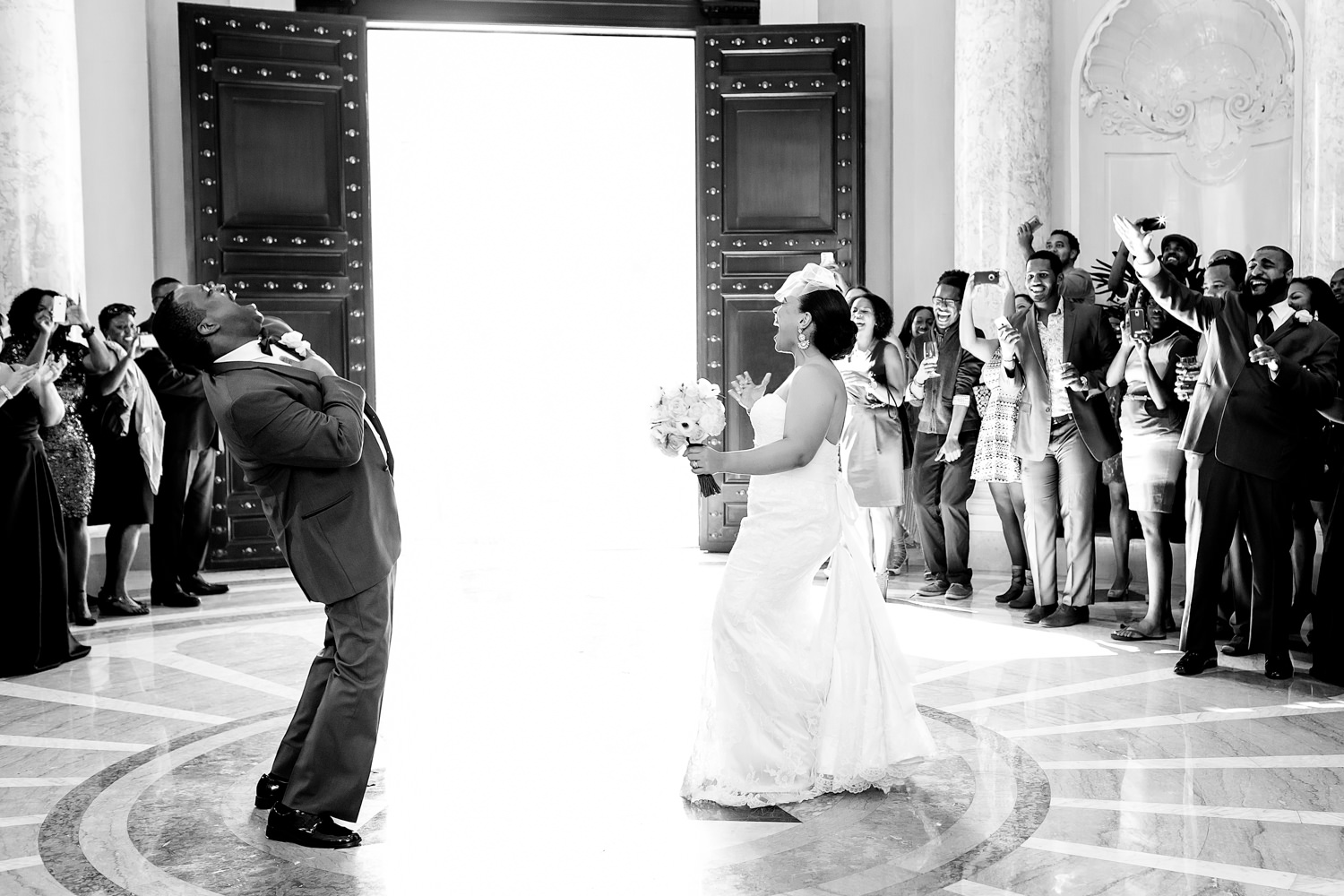 This wedding is at the Carnegie Library in Washington DC, The couple just entered the building at the beginning of their reception and they are cheering dramatically with the crowd also cheering them on, This joyous photo is of a black couple singing loudly and arching backward in dance to get the party started, Catching the moment, Procopio Photography, best top Washington DC photographer, best top Maryland photographer, best top Virginia photographer, best top DMV photographer, best top wedding photographer, best top commercial photographer, best top portrait photographer, best top boudoir photographer, modern fine art portraits, dramatic, unique, different, bold, editorial, photojournalism, award winning photographer, published photographer, memorable images, be different, stand out