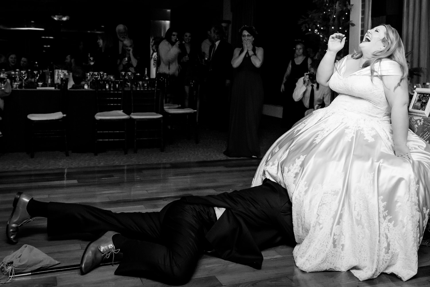 This is a Harbour View Wedding in Woodbridge, Virginia, this is a black and white photo of the groom crawling on the ground under the bride's dress, he is trying to retrieve the garter, she is hysterically laughing that the groom is lost under all of the layers of her dress, Procopio Photography, best top Washington DC photographer, best top Maryland photographer, best top Virginia photographer, best top DMV photographer, best top wedding photographer, best top commercial photographer, best top portrait photographer, best top boudoir photographer, modern fine art portraits, dramatic, unique, different, bold, editorial, photojournalism, award winning photographer, published photographer, memorable images, be different, stand out