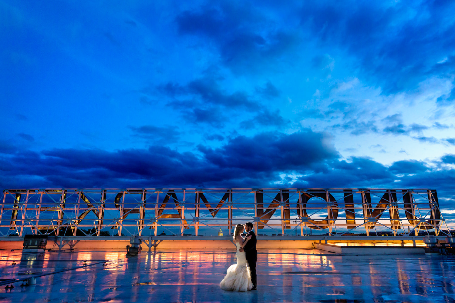 A Union Market, DC, Dock 5 wedding, This is one of my favorite venues, We took sunset photos on the rooftop behind the Union Market sign, The bride swishes her dress as the groom admires her, The sky is orange and bold as the sun is beginning to set, This was a different, offbeat, Procopio Photography, best top Washington DC photographer, best top Maryland photographer, best top Virginia photographer, best top DMV photographer, best top wedding photographer, best top commercial photographer, best top portrait photographer, best top boudoir photographer, modern fine art portraits, dramatic, unique, different, bold, editorial, photojournalism, award winning photographer, published photographer, memorable images, be different, stand out