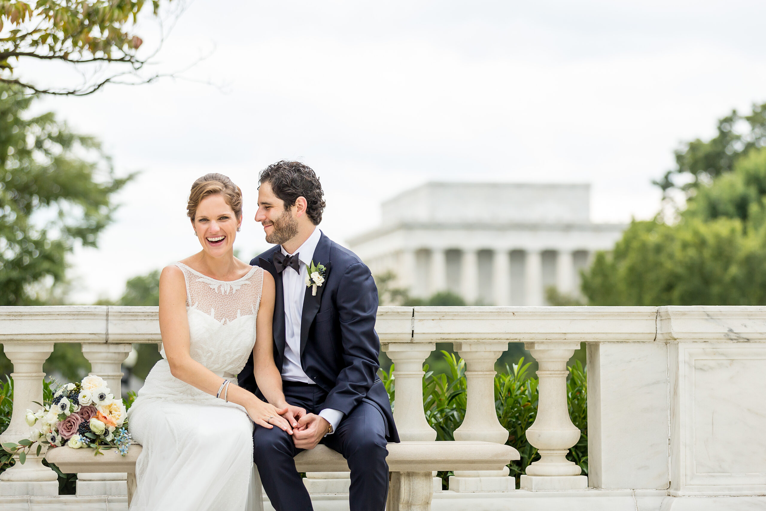 Procopio Photography, best top Washington DC photographer photography, best top Maryland photographer photography, best top Virginia photographer photography, best top DMV photographer photography, best top commercial photographer photography, best top wedding photographer photography, best top portrait photographer photography, best top boudoir photographer photography, modern fine art portraits, dramatic, unique, different, bold, editorial, photojournalism, award winning photographer, published photographer, memorable images, be different, stand out, luxe wedding, luxury wedding, luxury portraits, luxury boudoir, bespoke, bride and groom on a bench with the Lincoln Memorial behind them, bride is laughing, groom is smiling, natural portraits, they are sitting on a bench at Potomac View Terrace on their wedding day